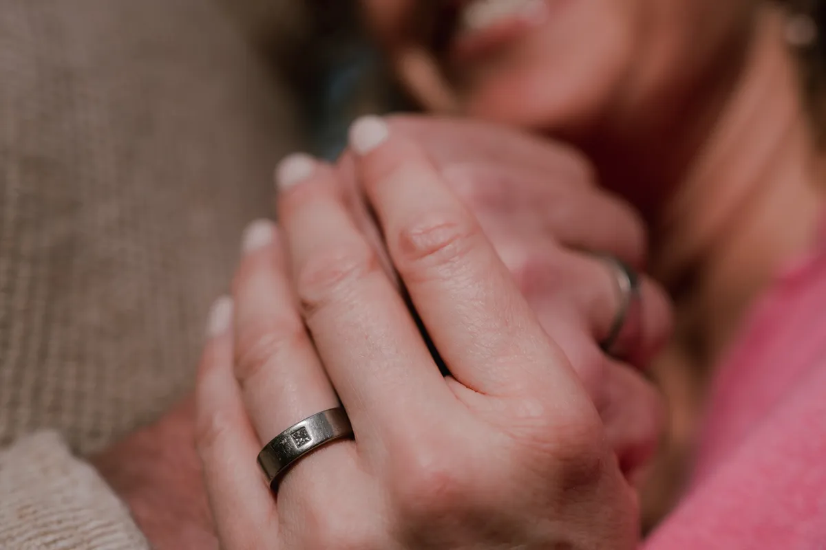 Twee handen die elkaar vasthouden, een vrouw lacht