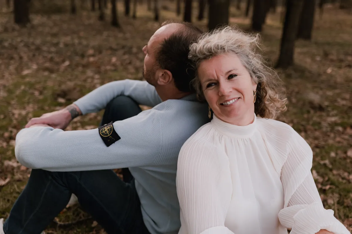 Een stel zit rug aan rug in het bos