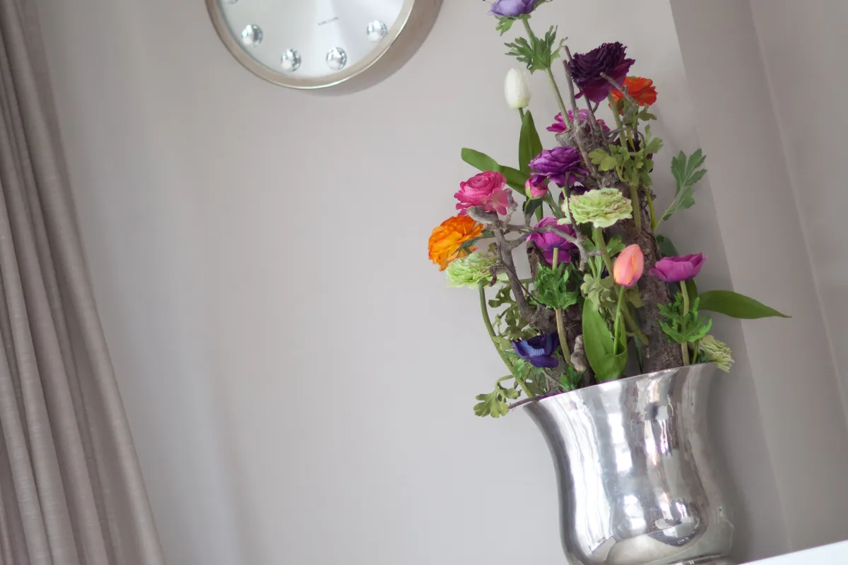De praktijkruimte: klok en bloemen op de vensterbank