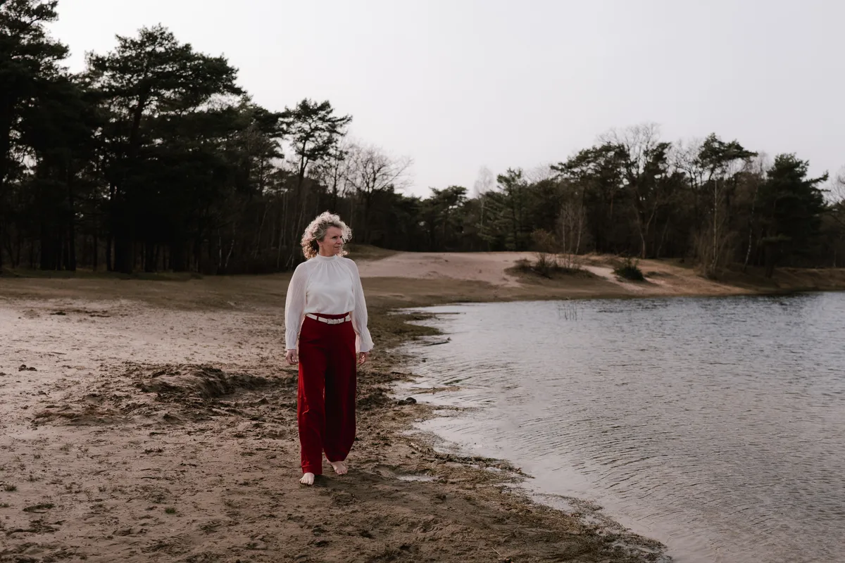 Een vrouw wandelt langs een meer op de hei